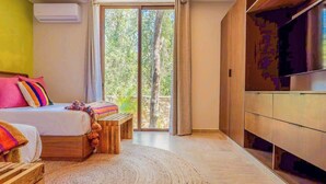 Un dormitorio con una cama, un banco de madera, un televisor y un ventanal grande.