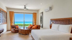 A bedroom with a large bed, a sofa, a wooden nightstand, and a view of the ocean. - Beachfront 5BR Villa Playacar, Private Pool (Playa del Carmen)