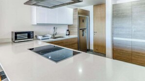 Une cuisine moderne équipée d’une cuisinière intégrée, d’un four à micro-ondes et d’appareils électroménagers en acier inoxydable.