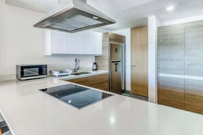 A modern kitchen with a built-in stove, microwave, and stainless steel appliances. - Ocean view condo w/ luxury pool rooftop access (Cancún)