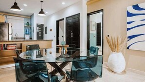 Una cucina moderna con forno integrato, un'area pranzo con tavolo e sedie in vetro e un grande specchio a parete.
