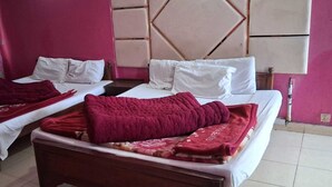 Habitación de hotel con dos camas, cada una con ropa blanca y mantas rojas.