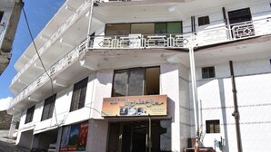 Un hotel con letrero, varios balcones y una escalera que conduce a la entrada.