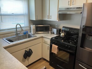 A kitchen with a sink, stove, microwave, toaster, and cabinets.