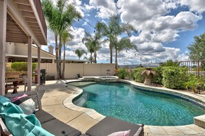 A swimming pool with a curved design, surrounded by lounge chairs and palm trees. - Palm Tree Lane Retreat in Murrieta: Private Pool, Spa, Loft, Balcony, Ideal Mid-Term Stay +Solar EV! (Murrieta)