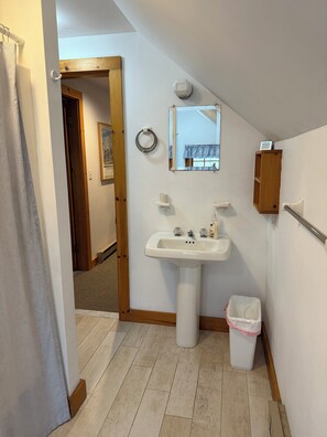 Ein Badezimmer mit Waschbecken, Spiegel, Handtuchhalter und Mülleimer.
