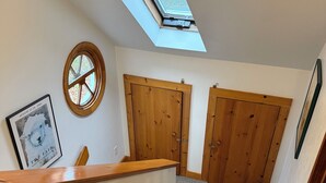 A staircase with carpeted steps, wooden doors, a skylight, and a framed picture on the wall.