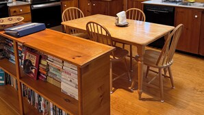 A kitchen with wooden cabinets, a microwave, a stove, and a dining table with chairs.