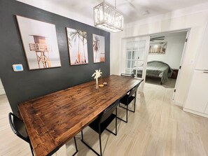 A dining area with a wooden table, black metal chairs, and a vase with white flowers. There are three framed pictures on the wall. - Hidden Oasis - 10 Min To Beach - Pool & Spa Retreat - Space for Boat/RV (Largo)