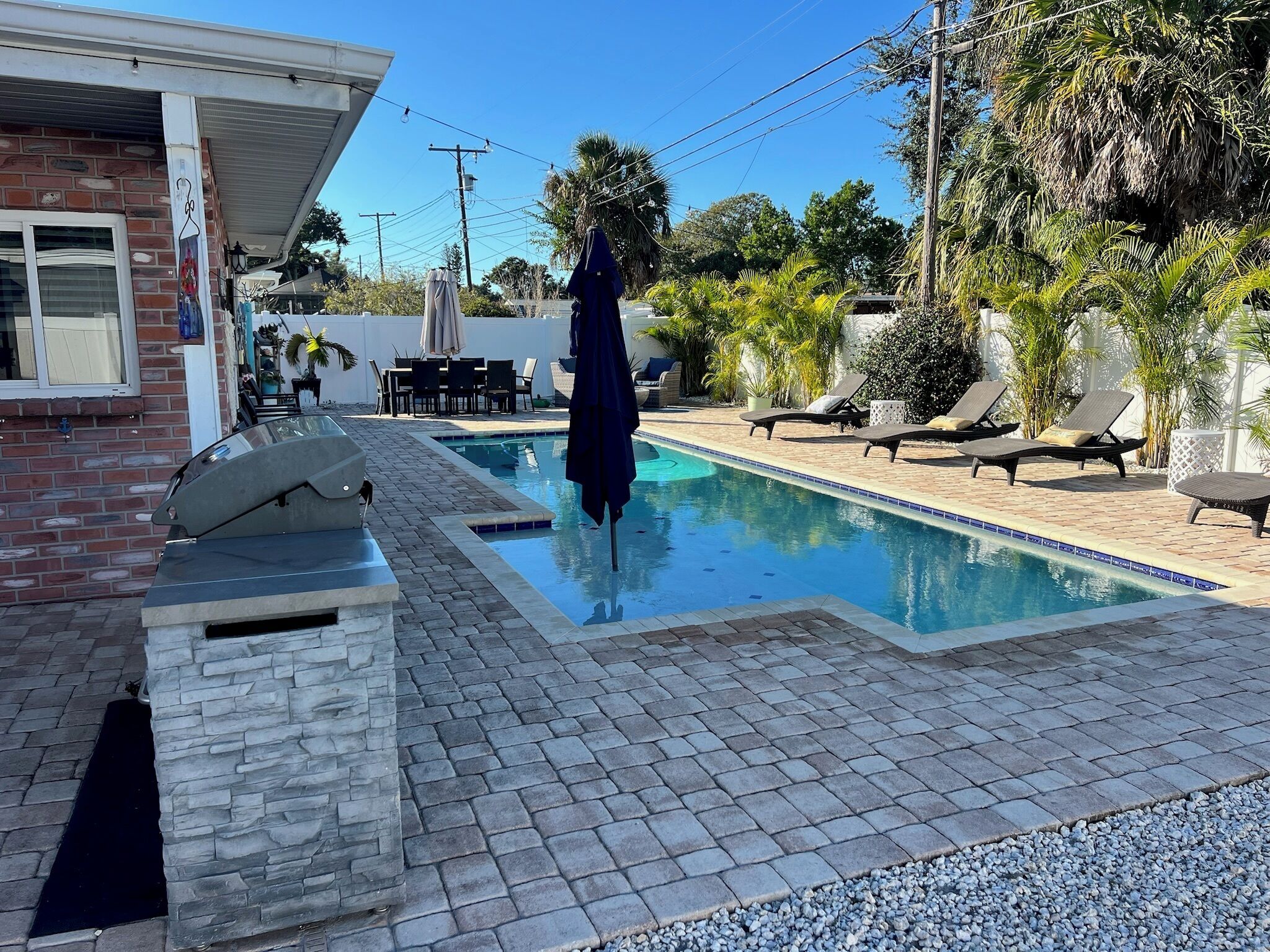 Une piscine avec des chaises longues, un espace patio et un bâtiment en briques.