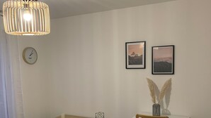 Ein moderner Essbereich mit Holztisch, weißem Stuhl, kleinem Beistelltisch und einer Pendelleuchte.
