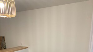 Ein graues Sofa, ein Holzboden, eine weiße Wand und eine hängende Leuchte.