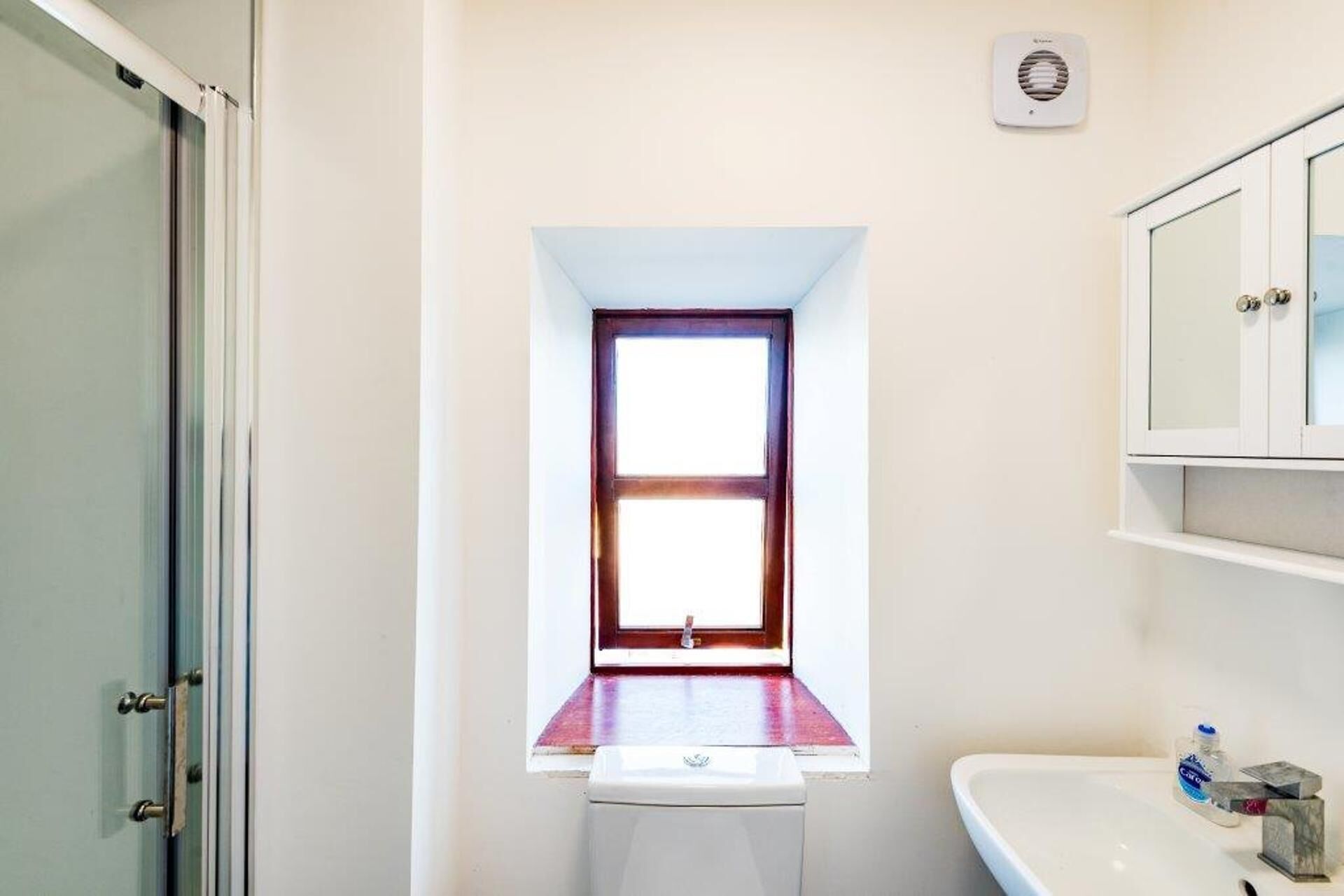 Une salle de bain avec une fenêtre, un lavabo et un miroir.