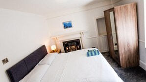 A bedroom with a bed, a fireplace, a wardrobe, and a painting on the wall. - Corporate - Business Travelers (Banff)