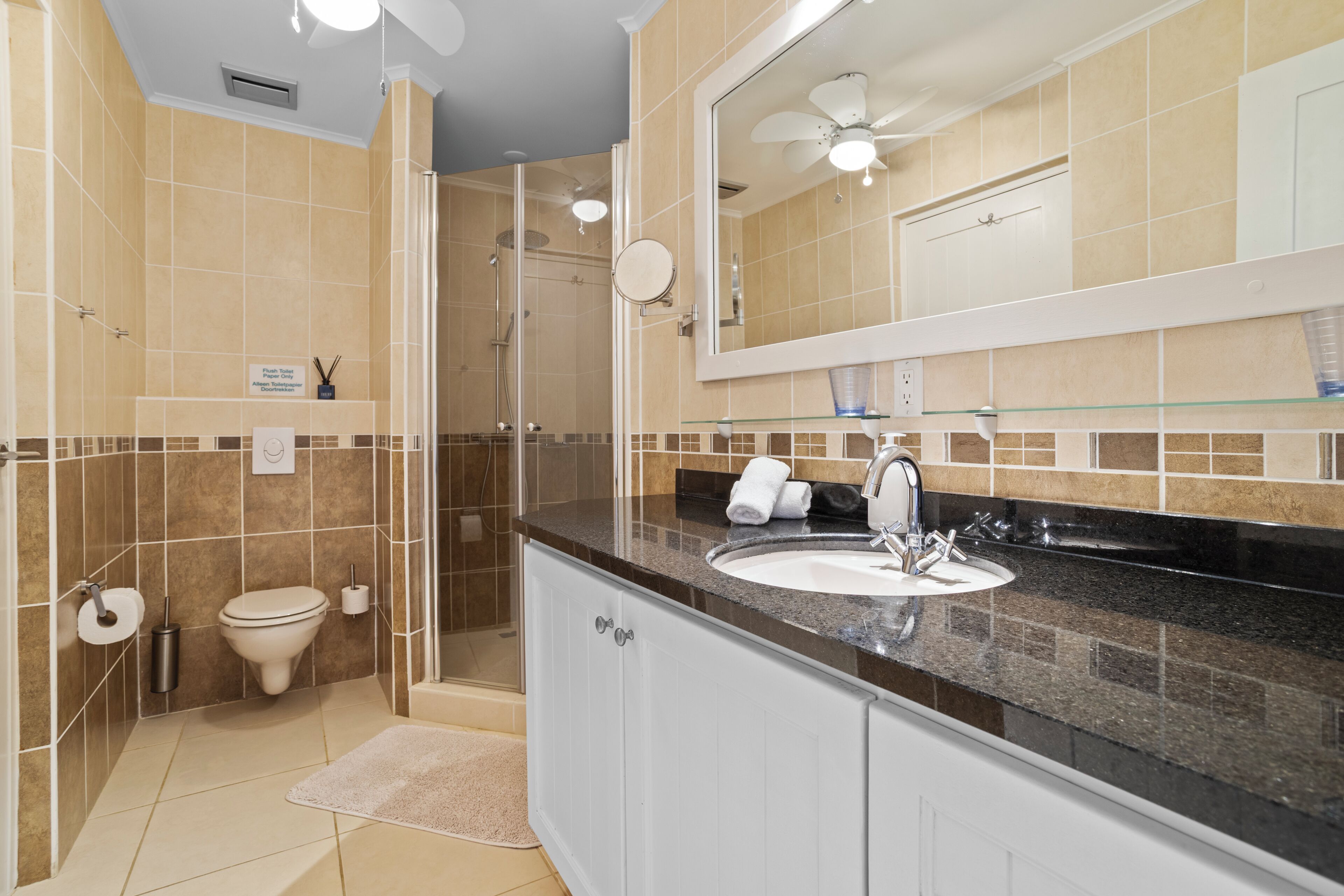 Une salle de bain équipée d’une douche, de toilettes, d’un lavabo et d’un grand miroir.