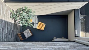 Een moderne buitenzitplaats met een bankje, een klein tafeltje en een bloempot.