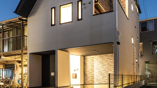 Een modern woonhuis met twee verdiepingen, een schuin dak, meerdere ramen en een zichtbare garage-ingang.