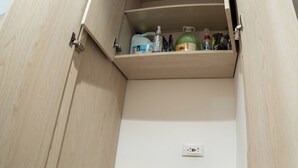 Un armario de madera con un estante que contiene varios objetos.