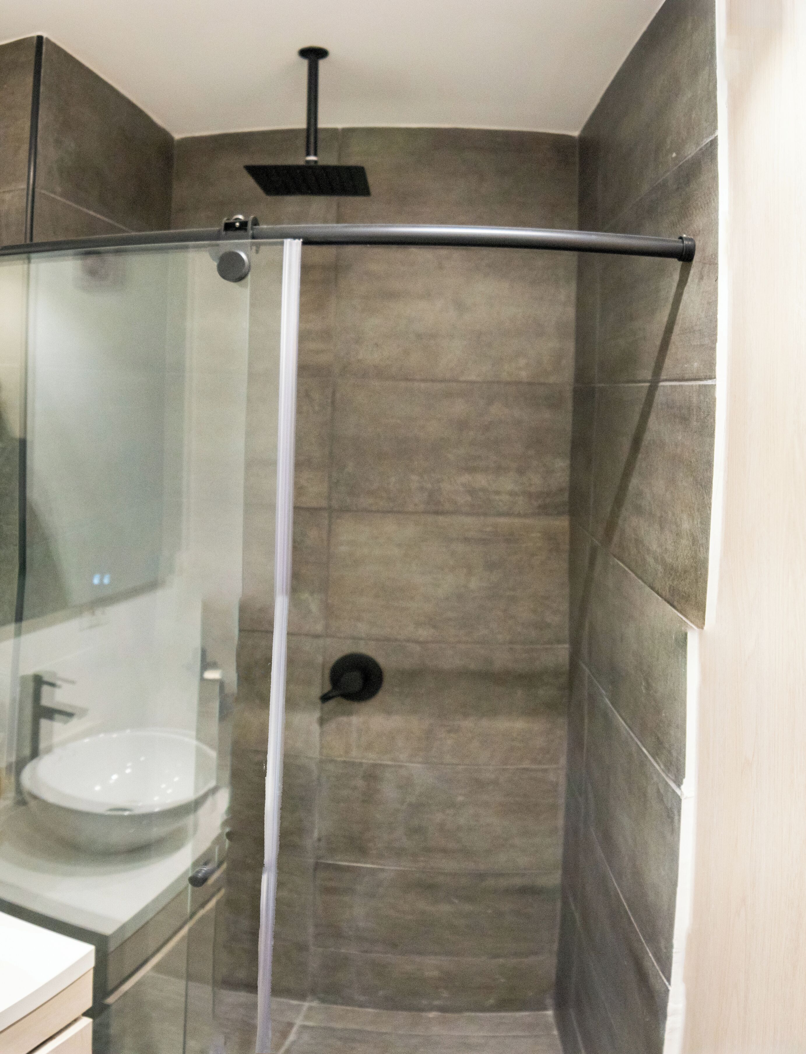 Un baño moderno con ducha de vidrio, lavamanos e inodoro.