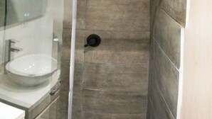Un baño moderno con ducha de vidrio, lavamanos e inodoro.