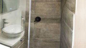 Un baño moderno con ducha de vidrio, lavamanos e inodoro.