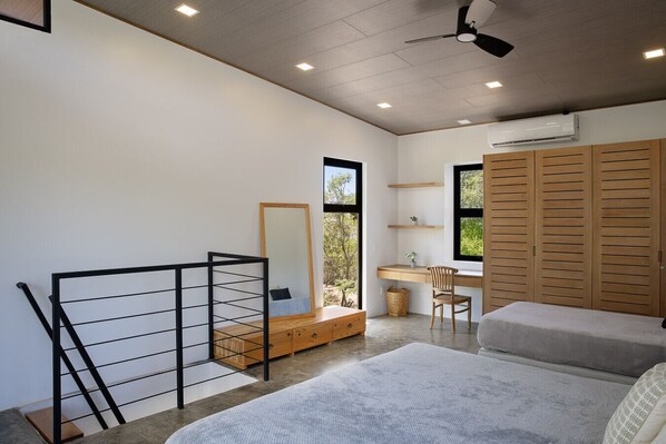A bedroom with a bed, a desk, a chair, a wardrobe, a mirror, and a staircase.