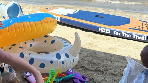 Une plage avec des piscines gonflables et une zone sablonneuse où se trouvent des jouets pour enfants.