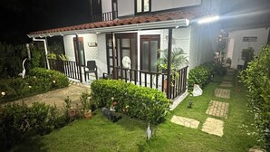 Une maison à deux étages avec un balcon, un jardin avec une pelouse et un chemin.