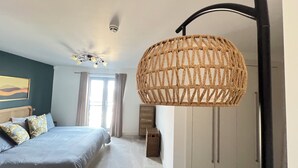 A bedroom with a bed, a ceiling fan, a large woven light fixture, a window with curtains, and a wall-mounted cabinet. - 2-bedroom apartment in lovely London with air conditioning (London)