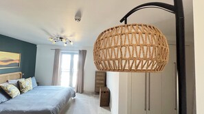 Un dormitori amb un llit, un ventilador de sostre, una lluminària gran teixida, una finestra amb cortines i un armari fixat a la paret.