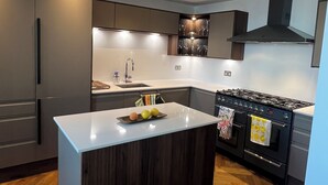 A modern kitchen with a central island, built-in appliances, and a herringbone wood floor. - 2-bedroom apartment in lovely London with air conditioning (London)