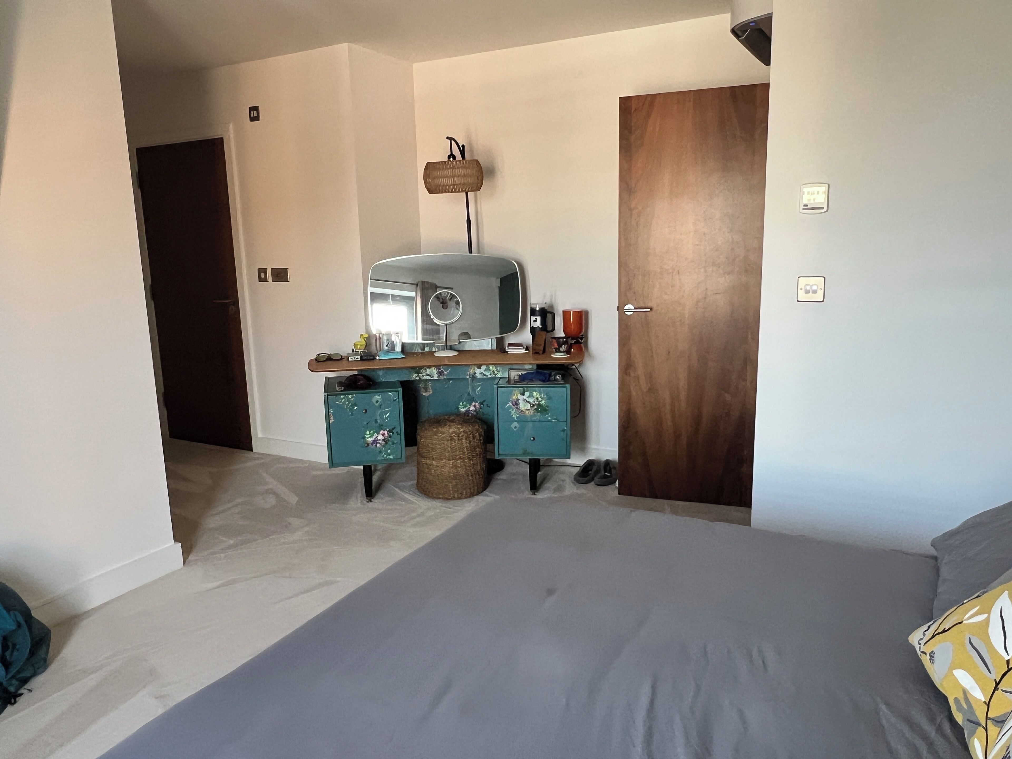 A bedroom with a bed, a dresser, a mirror, and a door.