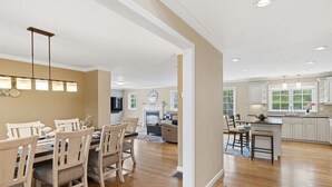 A spacious kitchen with wooden cabinets, a central island, and pendant lighting. - Hoppy Place: 066-M Expansive Deck area, Hot Tub, Walk to Salt Water (Mashpee)
