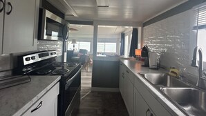 A modern kitchen with stainless steel appliances, a large window, and a view of the ocean. - Smith Beach cottage w/ private sunset (Cape Charles)