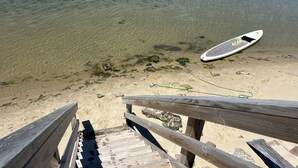 A wooden beach deck with a surfboard on the sand. - Smith Beach cottage w/ private sunset (Cape Charles)