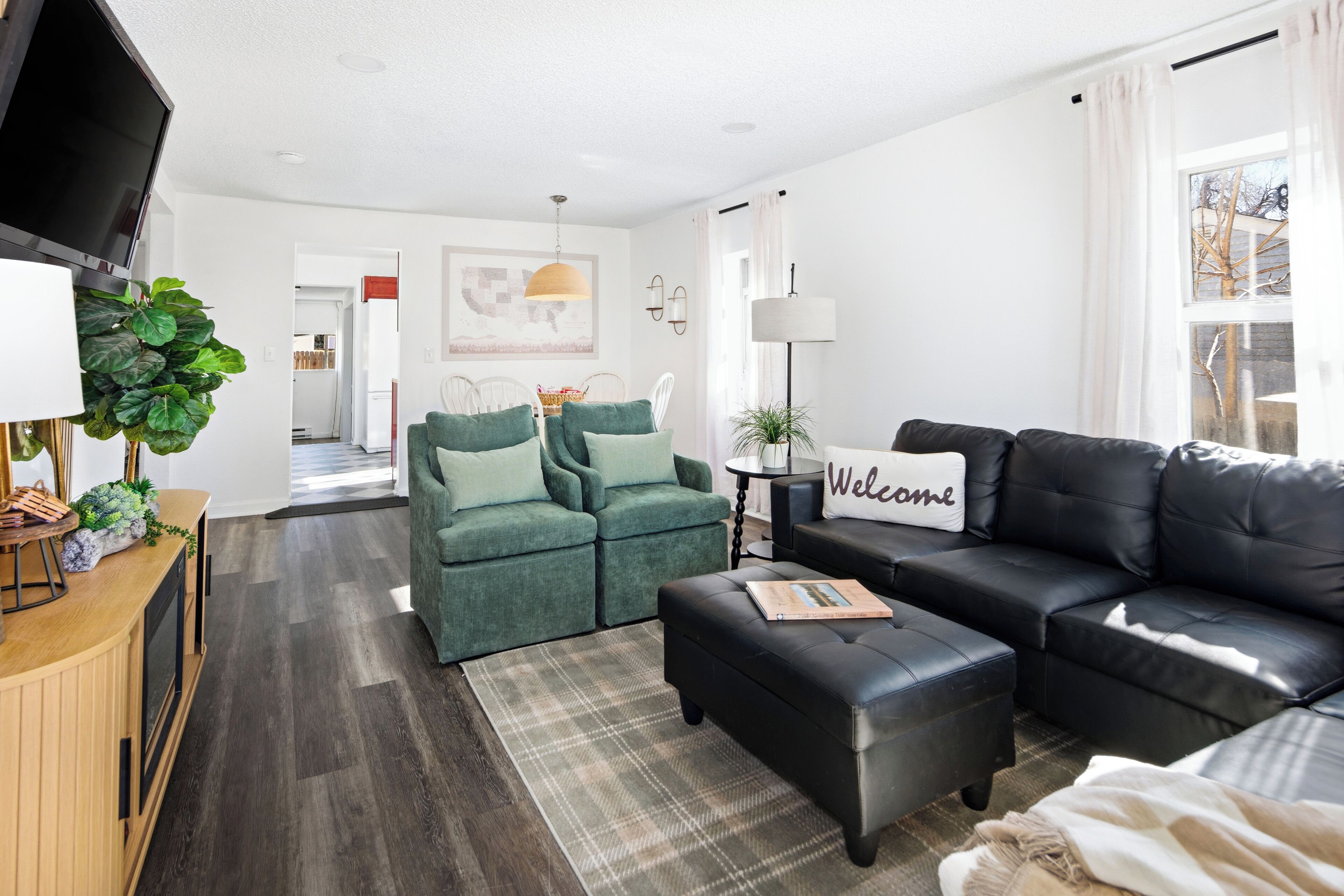 A modern living room with a sofa, ottoman, and a television.