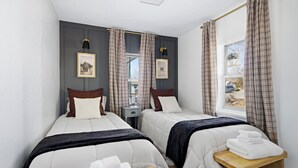 A hotel room with two beds, a nightstand, a window with curtains, and framed pictures on the wall. - Family Arcade Home Pets OK Near Red Rocks (Englewood)