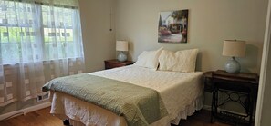 A bedroom with a bed, two bedside tables with lamps, a painting on the wall, and a window with curtains. - Masters Rental 2 Miles from the Augusta National (Augusta)