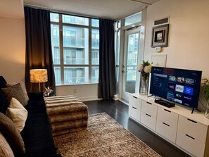 Un salon moderne doté d’une grande fenêtre, d’un téléviseur à écran plat et d’un canapé.