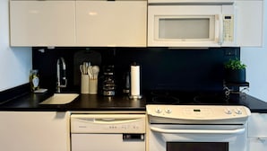 A modern kitchen with white cabinets, a microwave, a stove, and a dishwasher.
