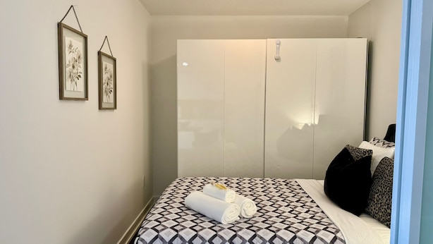 A bedroom with a bed, a wardrobe, and two framed pictures on the wall.