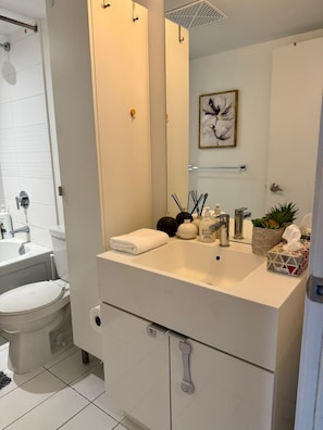 A modern bathroom with a white sink, mirror, and toilet.