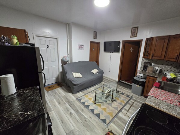 A compact living space with a sofa, a small kitchen area, and a door marked with a 'No Smoking' sign. - 3-bedroom 3 bathroom apartment in delightful Irvington, Free WiFi / Free Parking (Irvington)