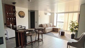 A spacious living area with a kitchen, a dining table, a sofa, and a large window. - Epic Suite 313 Family Airport 3Room10Pax (Pereira)