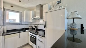 Moderni keittiö, jossa on valkoiset kaapit, musta työtaso, sisäänrakennettu uuni ja ikkuna.