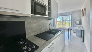 Une cuisine moderne équipée d’une cuisinière à gaz, d’un four à micro-ondes et offrant une vue sur l’extérieur.