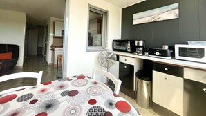 Una cocina compacta con comedor, microondas, cafetera y cubo de basura.