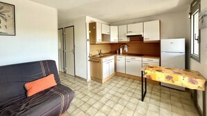 Una cocina compacta con armarios blancos, encimera de madera y una pequeña mesa de comedor.