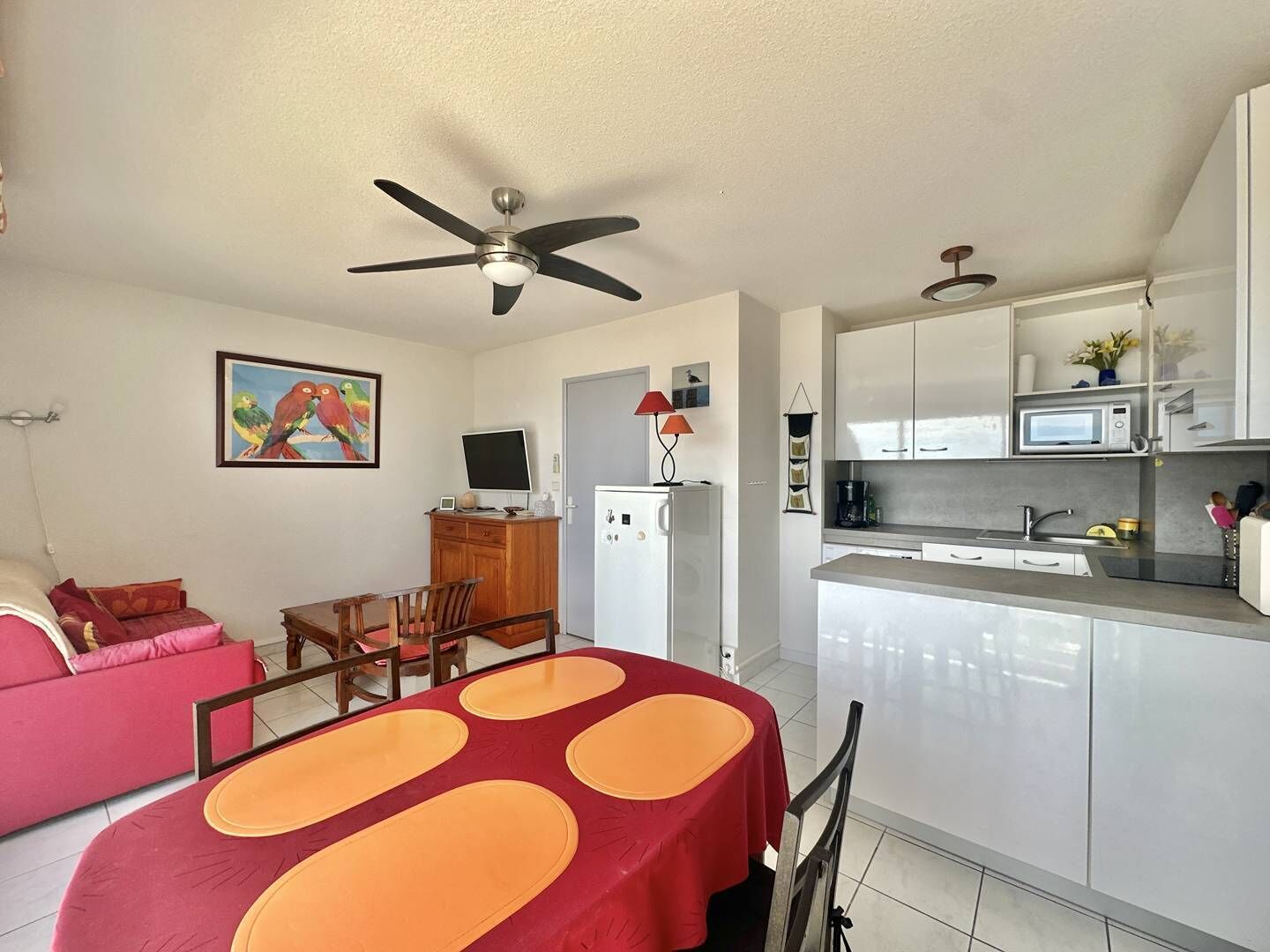 A compact living space with a dining area, kitchenette, and a ceiling fan.