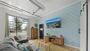 Een moderne woonkamer met een bank, salontafel en uitzicht op een stadsgezicht door grote ramen.
